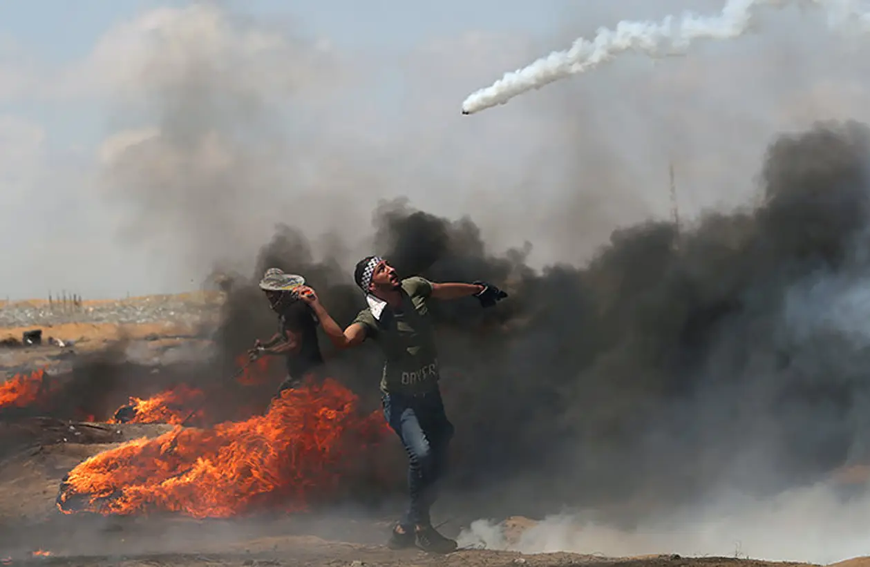Палестинец теннисной ракеткой отбивает израильскую газовую гранату