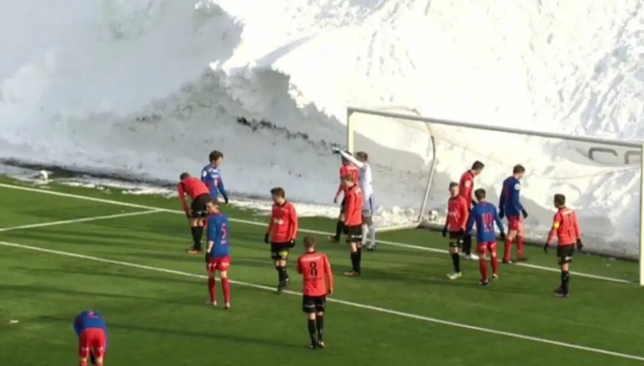 Футбол на поле, вокруг которого 6-метровая стена снега